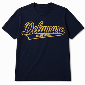 Może przedstawiać: Granatowa koszulka z napisem "Delaware BLUE HENS" w skrypcie z ż&oacute;łtymi i niebieskimi akcentami. Koszulka ma okrągły dekolt i kr&oacute;tkie rękawy. Tekst jest wyśrodkowany na piersi.