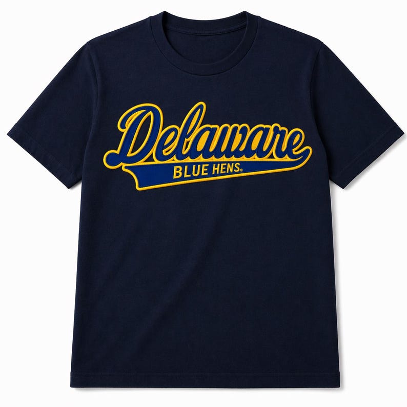 Może przedstawiać: Granatowa koszulka z napisem "Delaware BLUE HENS" w skrypcie z ż&oacute;łtymi i niebieskimi akcentami. Koszulka ma okrągły dekolt i kr&oacute;tkie rękawy. Tekst jest wyśrodkowany na piersi.