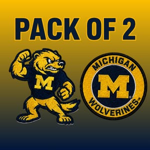 Op de afbeelding: Een set van 2 geborduurde patches met het logo van de Michigan Wolverines. Eén patch toont een gele en marineblauwe veelvraat-mascotte met een M op de borst, de andere is een ronde patch met de tekst MICHIGAN WOLVERINES.
