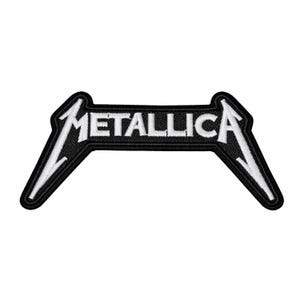 Puede incluir: Un parche bordado que presenta la palabra METALLICA en letras mayúsculas blancas sobre un fondo negro. El diseño incluye la fuente estilizada característica de la banda con extremos alargados y puntiagudos en la primera M y la última A, bordeado en negro.