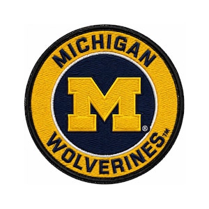 Puede incluir: Parche bordado circular con las palabras "MICHIGAN WOLVERINES". El parche tiene un borde amarillo y texto. El centro tiene un fondo azul marino con un logotipo "M" amarillo, adecuado para ropa o accesorios.