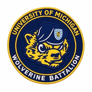 May include: A circular embroidered patch featuring a dark blue background with a yellow border. The text UNIVERSITY OF MICHIGAN and WOLVERINE BATTALION is stitched in white. A yellow wolverine mascot wearing a blue beret with a shield emblem.