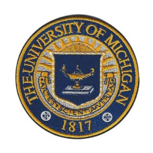 May include: A set of three ceramic mugs with a speckled, matte finish. The mugs are in shades of cream, light brown, and dark brown. Each mug has a simple, minimalist design and a rounded handle. The mugs are likely for coffee or tea.