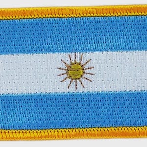 May include: Embroidered patch featuring the flag of Argentina. The design includes two light blue stripes, a white stripe in the center, and a yellow sun emblem. The patch has a yellow border.