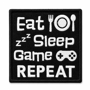 Puede incluir: Un parche cuadrado bordado en negro con texto e iconos en blanco. El diseño muestra las palabras Eat, Sleep, Game y REPEAT, acompañadas de un tenedor, un plato, una cuchara, símbolos zzz y un icono de mando de juego en hilo blanco.