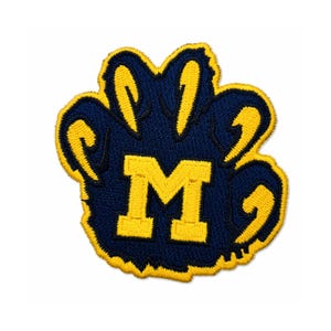 May include: Embroidered patch featuring a navy blue paw print with yellow accents and a yellow "M" in the center. The patch has a yellow border and is likely for apparel or accessories.