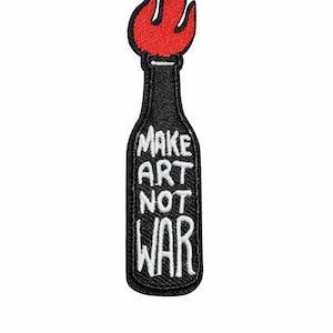 May include: Embroidered patch featuring a black bottle shape with a red flame at the top. The patch has the words "MAKE ART NOT WAR" in white, stylized lettering. This patch is suitable for jackets, bags, or other fabric items.