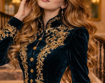 Puede incluir: Un vestido de terciopelo verde azulado oscuro con intrincados bordados dorados. El vestido presenta un cuello alto, mangas largas y botones dorados decorativos. Los detalles dorados adornan el corpiño, las mangas y el escote, creando un aspecto lujoso y elegante.