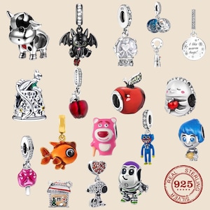 May include: A selection of silver charms with diverse designs, such as a cow, a bat, a snow globe, an apple, a hedgehog, a goldfish, a pink bear, a blue monster, and a character with blue hair. The charms are detailed and colourful.