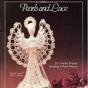 May include: A white crochet angel with pearl accents, from a book titled "Pearls and Lace." The angel has outstretched wings and a halo. The book cover also features text that reads "21 Crochet Projects Including 8 Pearl Projects."