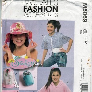 May include: A vintage McCall's Fashion Accessories pattern. The cover features images of a girl modeling various accessories, including a floral sun hat, a blue cape, a pink poncho, a purple hat, a pink backpack, and a teal bag. The text "Sassy Girl" is also visible.