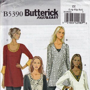 May include: Butterick B5390 sewing pattern featuring four tunic designs. The pattern includes a variety of styles, including a red tunic with gold trim, a black and white polka dot tunic, a black tunic with lace, and a white tunic with gold trim.