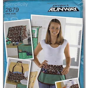 May include: Simplicity sewing pattern 2679, featuring a woman wearing a sewing apron. The pattern includes images of sewing accessories and projects. The apron has a brown top with safety pins and scissors, a green middle, and a brown trim.