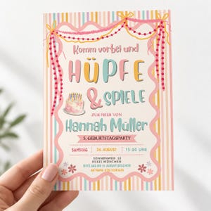 May include: A rectangular birthday party invitation card featuring a pastel striped background, a scalloped border with pink beaded garlands, and a small cake illustration. The text reads: Komm vorbei und H&Uuml;PFE & SPIELE ZUR FEIER VON Hannah M&uuml;ller.