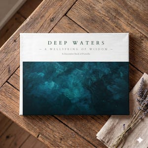 May include: A decorative book titled "Deep Waters" with a teal and white cover, resting on a wooden surface. The book's cover features the text "Deep Waters - A Wellspring of Wisdom - A Decorative Book of Proverbs."