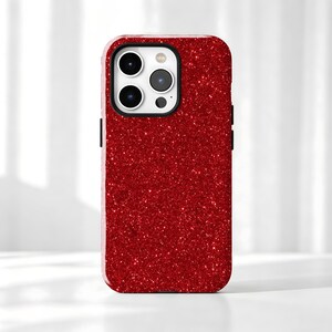 May include: A smartphone case featuring a vibrant red glitter finish across the entire back surface. The case includes a rectangular cutout at the top left corner to accommodate a triple-lens camera system and a flash, with black edges.