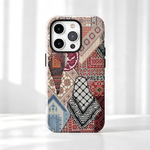 Könnte beinhalten: Eine Smartphone-Hülle mit einem mehrfarbigen Patchwork-Design aus traditionellen Kreuzstich-Stickmustern. Das Design umfasst rote, schwarze, weiße und blaue geometrische Motive, wobei das Wort PALESTINE teilweise in schwarzen Buchstaben sichtbar ist.