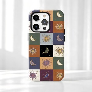 Può includere: Una custodia per telefono rettangolare con un motivo a griglia di quadrati in vari colori, tra cui verde scuro, arancione, nero, blu e crema. Ogni quadrato contiene un'illustrazione stilizzata di un sole o di una luna crescente.