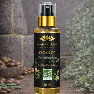 Puede incluir: Una botella de vidrio transparente de Aceite de Arg&aacute;n Moroccan Glow con una etiqueta negra y dorada. La etiqueta dice "ARGAN OIL With Verbena Scent For Hair, Face & Body" e incluye un logotipo de certificaci&oacute;n. La botella contiene 80 ml de aceite.