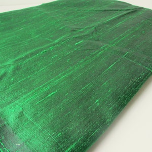 Può includere: Primo piano di un tessuto verde con un aspetto testurizzato e tessuto. Il tessuto ha una lucentezza sottile e una sensazione liscia e setosa.