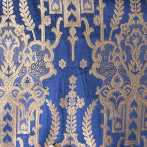 May include: Blue fabric with a gold damask pattern. The pattern features intricate floral designs and repeating motifs.