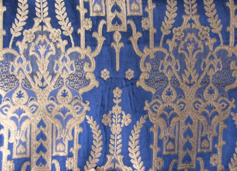 May include: Blue fabric with a gold damask pattern. The pattern features intricate floral designs and repeating motifs.
