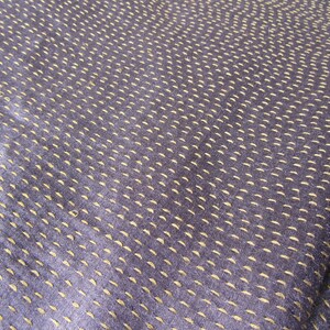 Peut inclure: Gros plan sur un tissu bleu fonc&eacute; avec un motif subtil de petites coutures jaune clair. Le tissu a une surface lisse et l&eacute;g&egrave;rement textur&eacute;e.