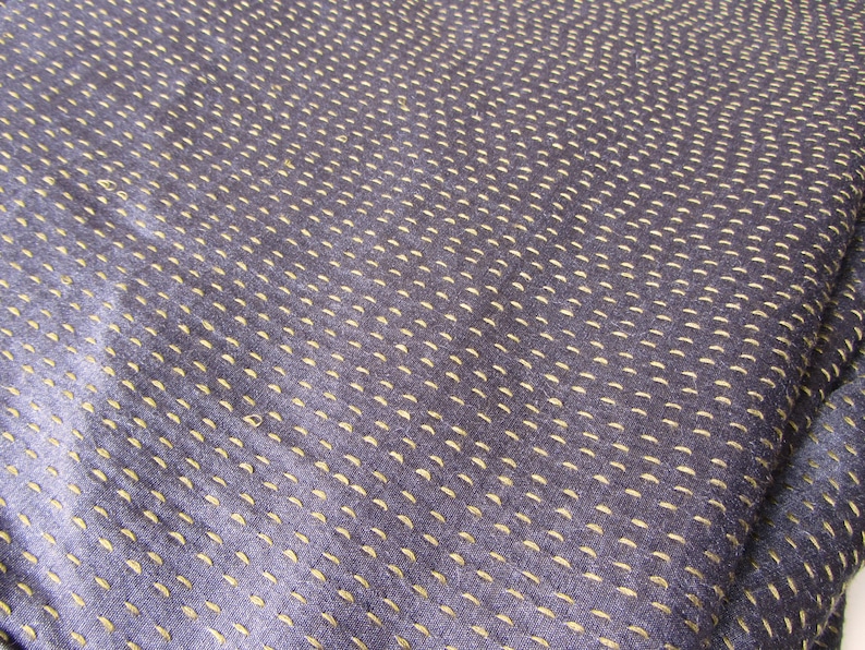 Peut inclure: Gros plan sur un tissu bleu fonc&eacute; avec un motif subtil de petites coutures jaune clair. Le tissu a une surface lisse et l&eacute;g&egrave;rement textur&eacute;e.