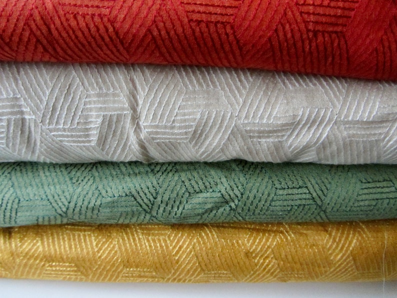 May include: Four fabric swatches with a geometric pattern. The swatches are stacked on top of each other. The top swatch is red, the second is beige, the third is green, and the bottom swatch is yellow.