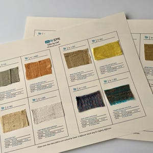 Peut inclure: Plusieurs cartes d'échantillons de tissus présentent des échantillons de soie brute aux couleurs variées. Les cartes affichent des échantillons dorés, beiges, cuivrés et bleus, avec des détails tels que le nom et le poids du tissu. Mesures en cm et grammes.