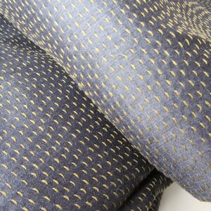 Peut inclure: Gros plan sur un tissu bleu fonc&eacute; avec un motif subtil de surpiq&ucirc;res jaunes. Le tissu a une texture douce.