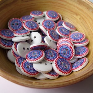 May include: A bowl filled with white wooden buttons with a red, blue, and white swirl design.