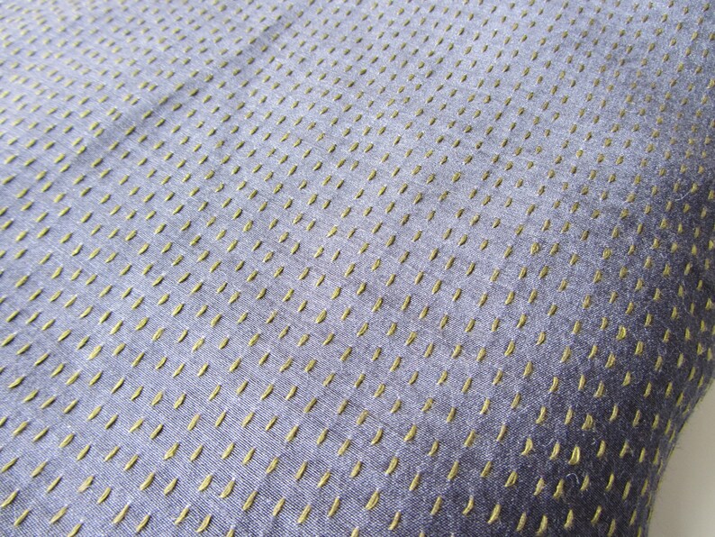Peut inclure: Gros plan sur un tissu bleu avec un motif subtil de petites coutures dor&eacute;es. Le tissu a une apparence textur&eacute;e et tiss&eacute;e.