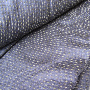 Peut inclure: Gros plan sur un tissu bleu avec une texture subtile. Le tissu pr&eacute;sente un motif de petites coutures jaunes qui cr&eacute;ent un effet de points.