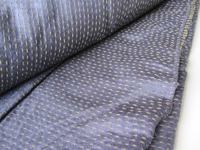 Peut inclure: Gros plan sur un tissu bleu avec une texture subtile. Le tissu pr&eacute;sente un motif de petites coutures jaunes qui cr&eacute;ent un effet de points.