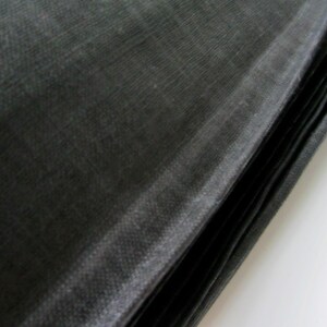 May include: A stack of black fabric, possibly for sewing or crafting projects. The fabric has a smooth, silky texture.