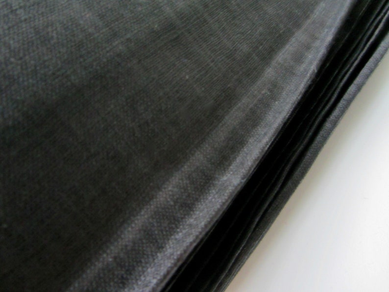 May include: A stack of black fabric, possibly for sewing or crafting projects. The fabric has a smooth, silky texture.