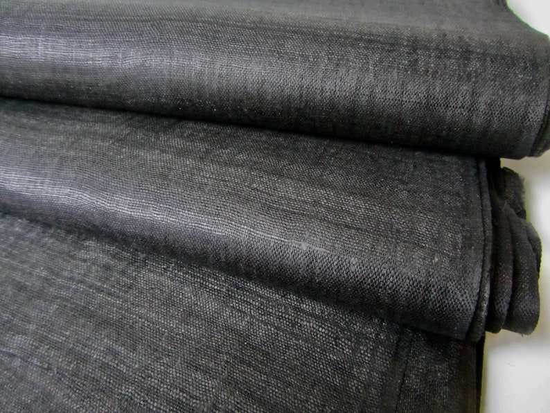 May include: Black linen fabric folded in layers, showing the texture and weave of the material.