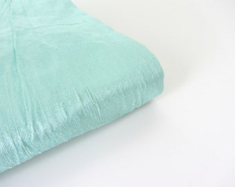 Könnte beinhalten: Ein hellblauer Stoff mit einer geknitterten Textur. Der Stoff ist in der Mitte gefaltet und die Kanten sind sichtbar.