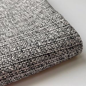 Puede incluir: Primer plano de una tela texturizada en blanco y negro. La tela tiene un patrón tejido y una textura suave y ligeramente peluda.