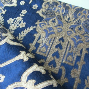May include: Blue fabric with a gold and blue damask pattern. The fabric has a raised texture and a luxurious feel.