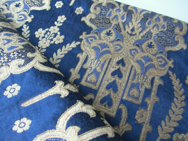 May include: Blue fabric with a gold and blue damask pattern. The fabric has a raised texture and a luxurious feel.