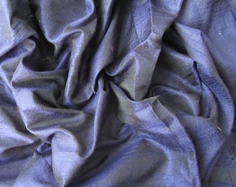 Könnte beinhalten: Nahaufnahme eines tiefblauen Stoffes mit dezentem Glanz. Das Material ist stark drapiert und erzeugt weiche Falten und Schatten. Die Textur erscheint glatt, mit sichtbaren Webdetails. Der Gesamteffekt ist luxuriös und elegant.