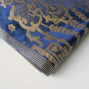 May include: A close-up of a blue fabric with a gold damask pattern. The fabric has a subtle sheen and a soft texture.