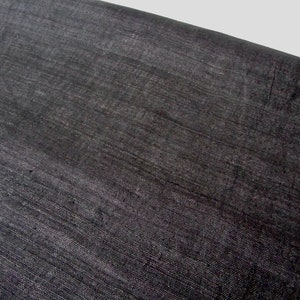May include: A close-up of a black fabric with a subtle, woven texture. The fabric has a smooth, slightly shiny surface.