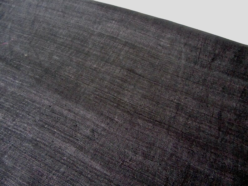 May include: A close-up of a black fabric with a subtle, woven texture. The fabric has a smooth, slightly shiny surface.