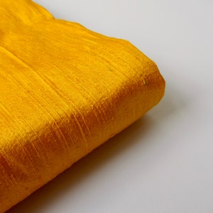 May include: A close-up of a folded piece of yellow fabric with a silky texture.