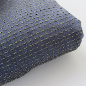 Peut inclure: Gros plan sur un tissu bleu avec une texture subtile. Le tissu pr&eacute;sente un motif de petites coutures jaunes qui cr&eacute;ent un design en forme de grille.