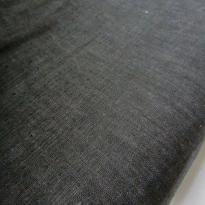 May include: A close-up of a black fabric with a woven texture. The fabric has a slightly rough feel and a subtle sheen.