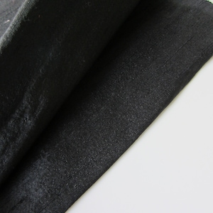 K&ouml;nnte beinhalten: Nahaufnahme eines schwarzen Stoffes mit glatter, seidenartiger Textur. Der Stoff ist in der Mitte gefaltet, wodurch die Unterseite sichtbar wird.
